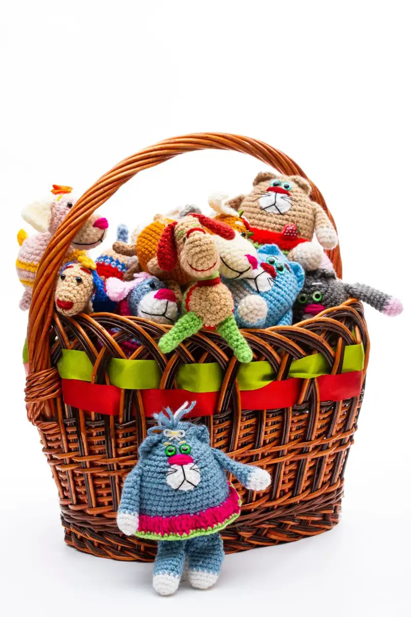 Wicker basket full of colorful handmade crochet animal toys with ribbon trim