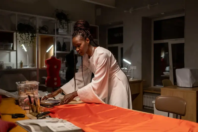 Designer arranging papers over orange fabric in a studio