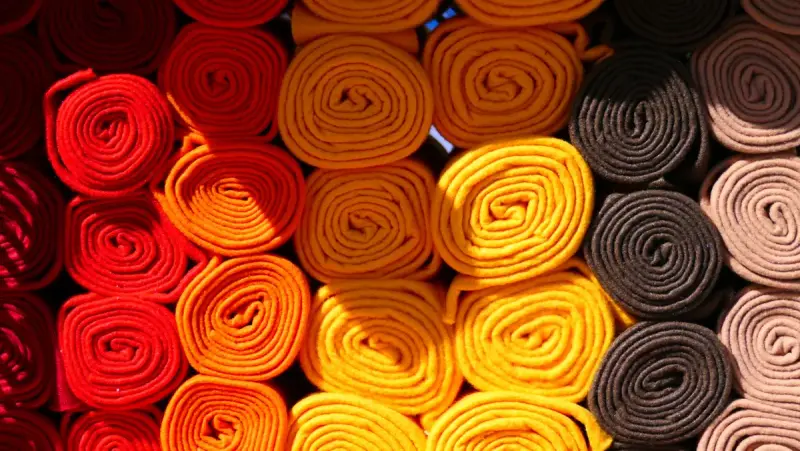 Rolls of red, orange, yellow and brown fabric stacked in rows