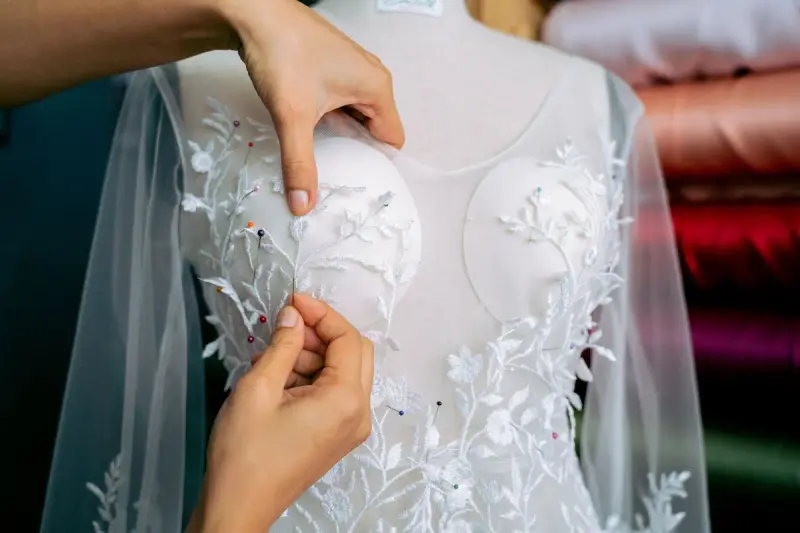 Hands adjusting lace on a dress in a fashion atelier