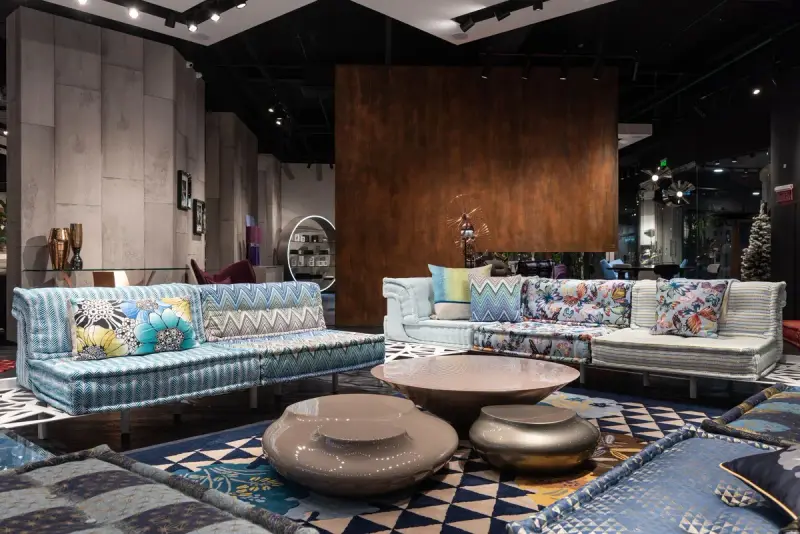 Patterned sectional sofas, round metal coffee tables and geometric rugs in a dark showroom