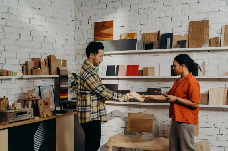 Man and woman compare wood finish samples on shelves in a bright showroom