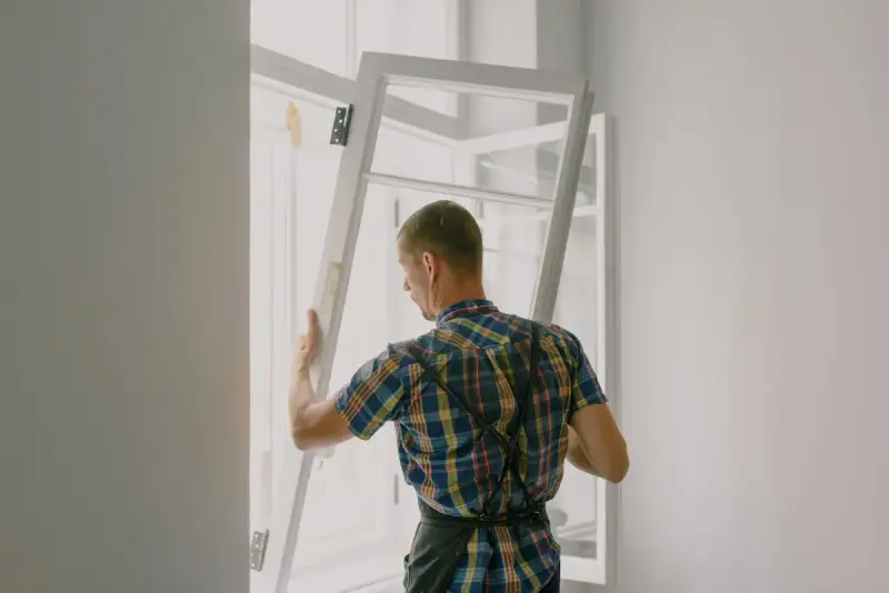 Fitter in a checkered shirt attaching a new window frame during a renovation