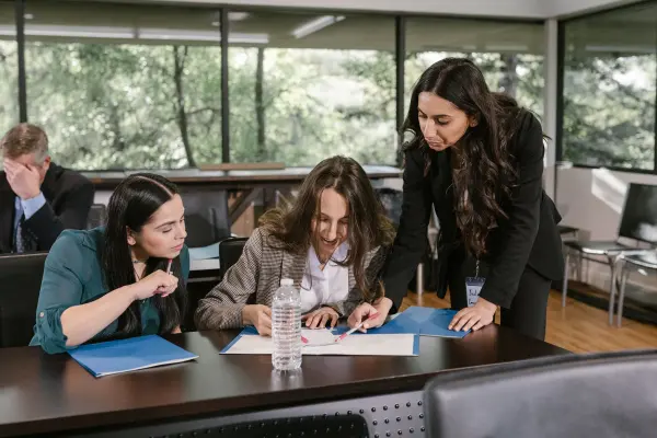 Three businesswomen discussing documents around an office table