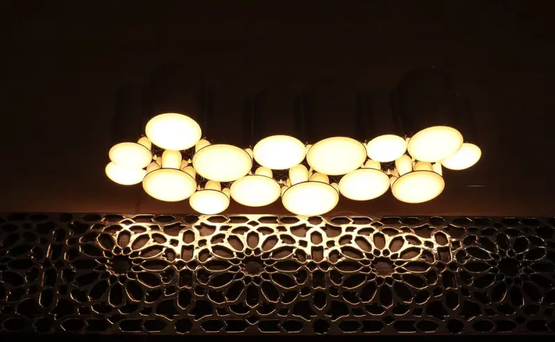 Ceiling lights behind an artistic panel casting a warm glow in a dark modern room