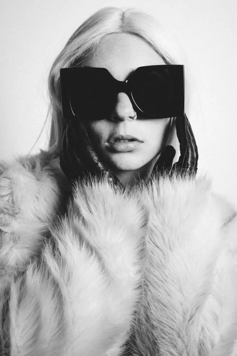 Black and white portrait of a woman in oversized square sunglasses and a fur coat