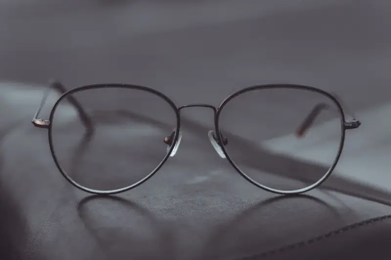 Aviator eyeglasses resting on a leather surface