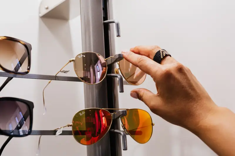 Hand selecting mirrored aviator sunglasses from a display stand