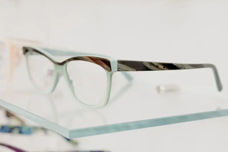 Fashion eyeglasses arranged on a glass shelf in a modern optical store