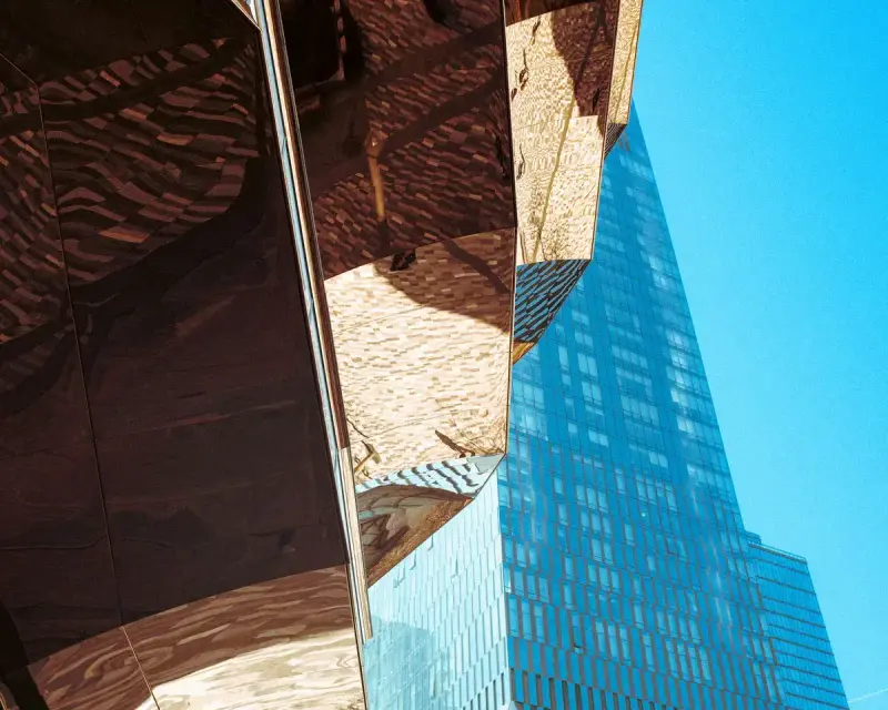 Copper-clad Vessel beside a glass tower at Hudson Yards under a blue sky