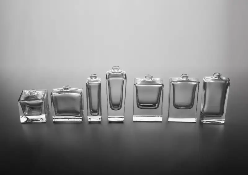 Row of empty clear glass perfume bottles in different shapes on gray