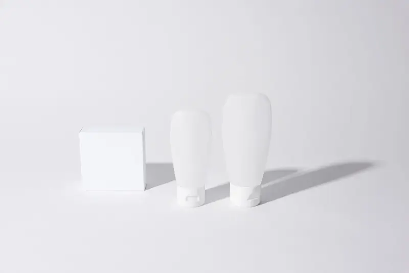 Blank white cosmetic bottles and a box on a white table