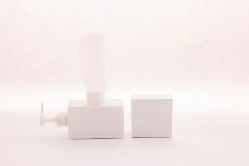 White pump dispenser and a matching square box on a soft white background