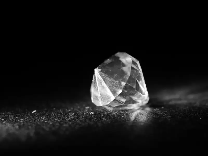 Macro shot of a loose faceted diamond catching light on a dark surface