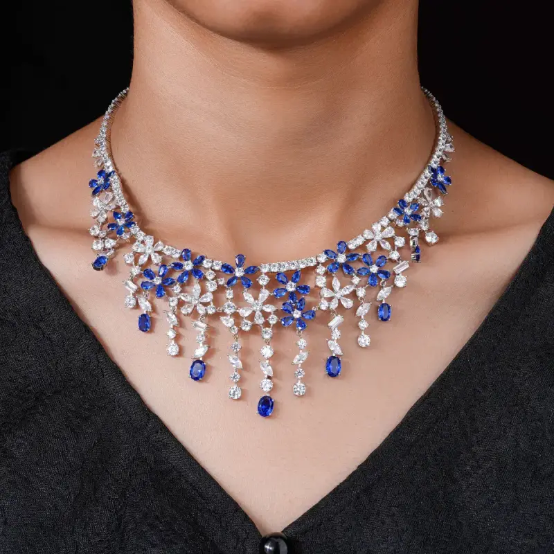 Sapphire and diamond fringe necklace worn over a dark knit, close-up