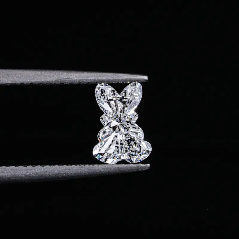 Fancy-cut loose diamond held in tweezers against a black background
