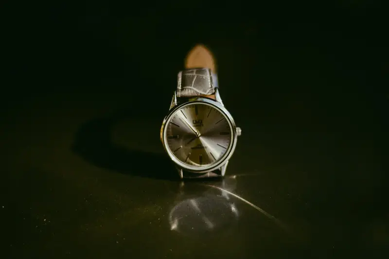 Classic silver wristwatch with a leather strap on a reflective surface