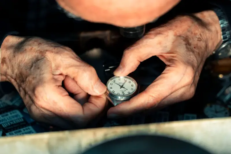 Watchmaker's hands repairing a wristwatch under magnification