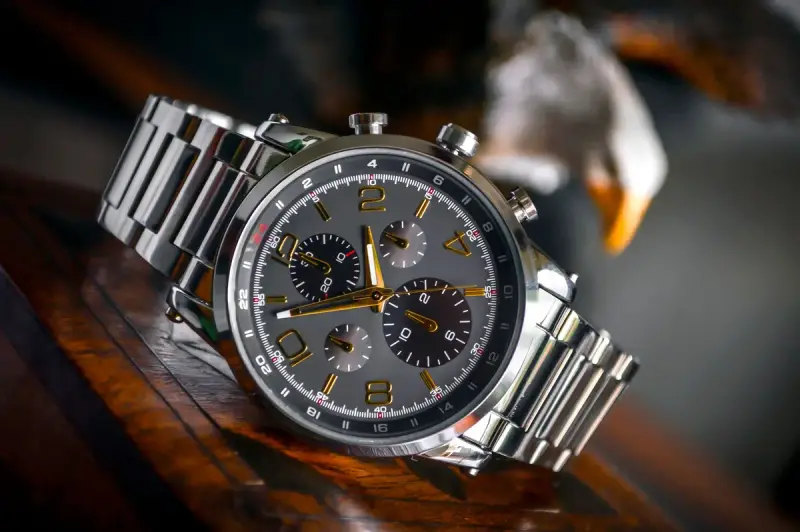 Wristwatch with a stainless steel bracelet laid on wood