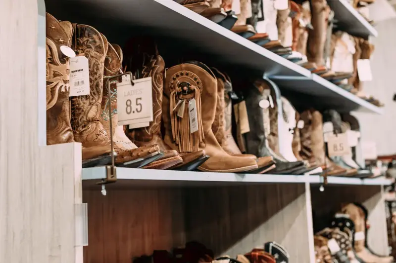 Rows of leather cowboy boots displayed on shelves in a footwear store