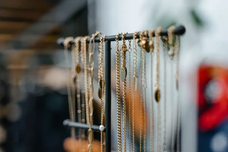 Gold necklaces hanging from a jewelry display stand