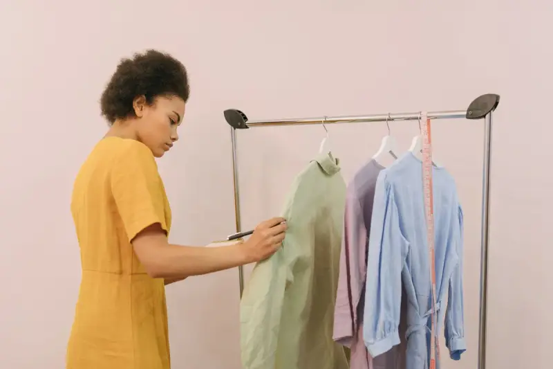 A woman in a yellow dress checks clothing items on a boutique rack