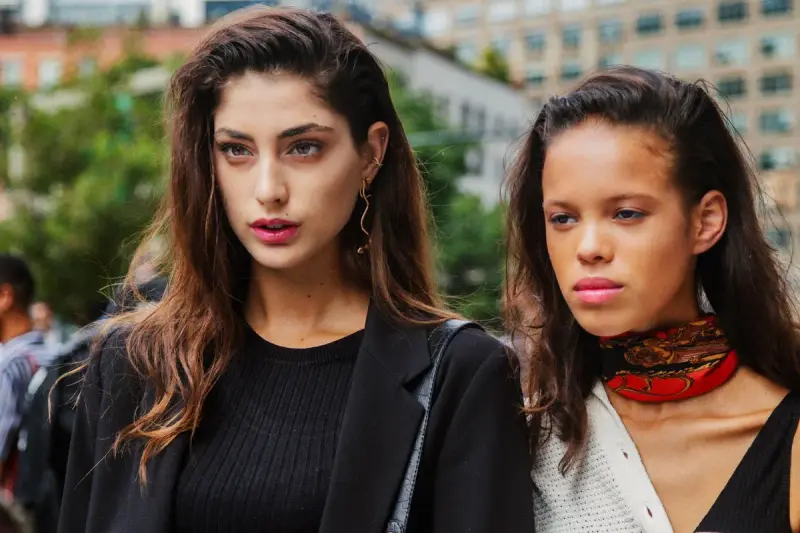 Two fashion models in black jackets and a red choker on a New York street