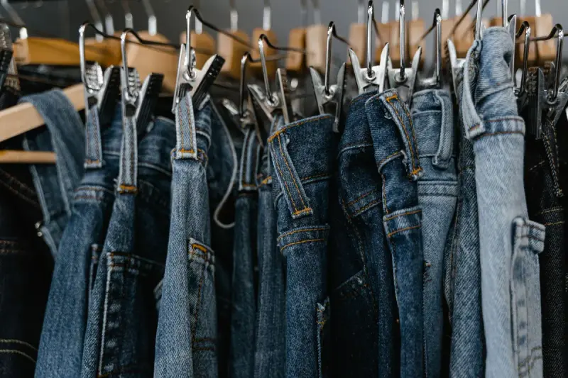 Close view of denim jeans in several washes hanging from a rail