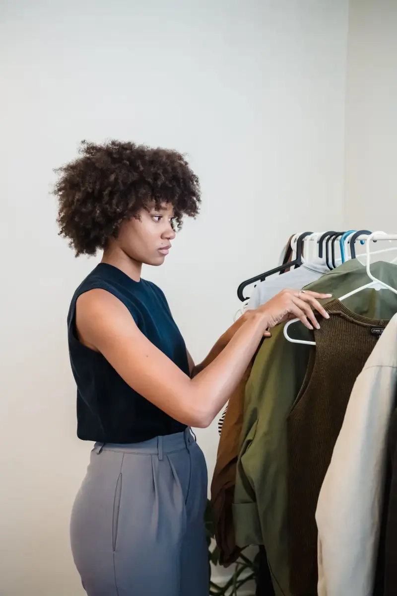 Woman selecting a garment from a rail of hangers in a white room