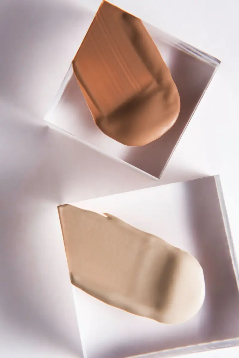 Two foundation shade swatches smeared on clear acrylic blocks
