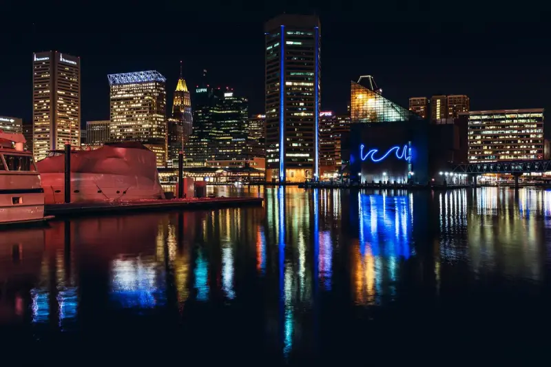 Baltimore skyline lit at night with colorful reflections on the Inner Harbor