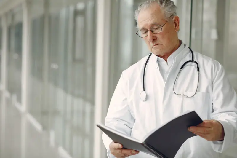Senior physician with a stethoscope reading clinical records
