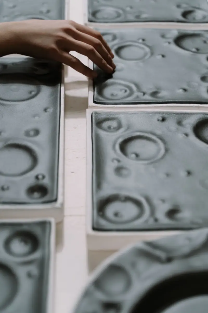 Hand resting on textured production molds in a manufacturing workshop