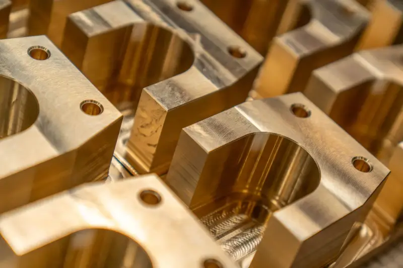 Rows of precision-machined brass blocks with drilled holes and milled curved pockets