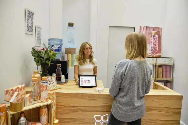 A professional welcoming a visitor at a contemporary beauty-clinic reception desk
