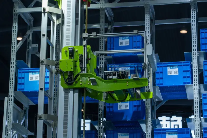 Automated warehouse system with a robotic arm handling blue storage crates