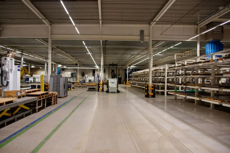 Spacious warehouse interior with storage racks, pallets and equipment under bright lights