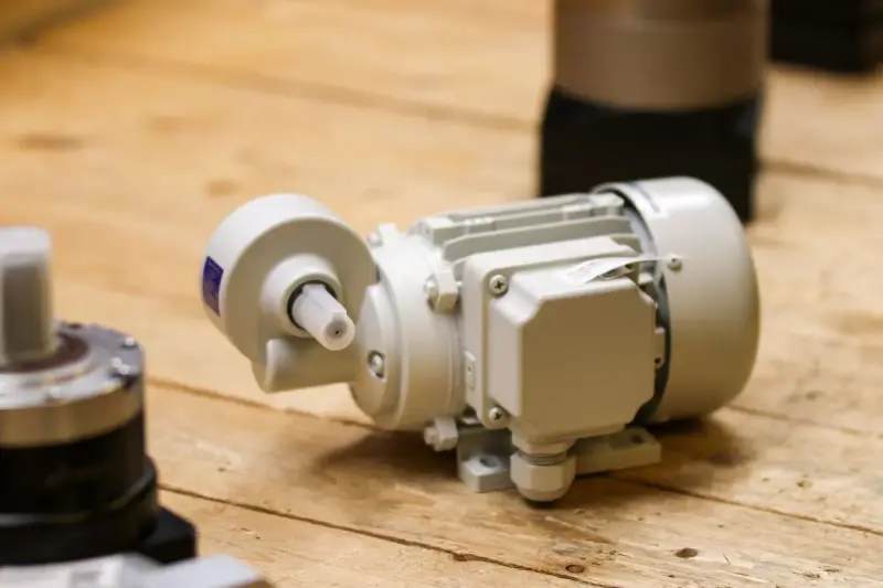 Compact white electric gear motor resting on a wooden workbench