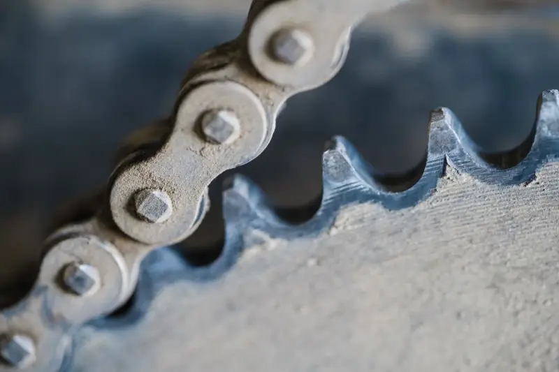 Close-up of a roller chain meshing with a worn steel sprocket