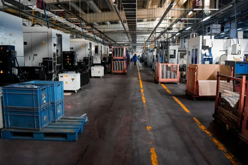 Long factory floor lined with CNC machines, parts bins and wire crates