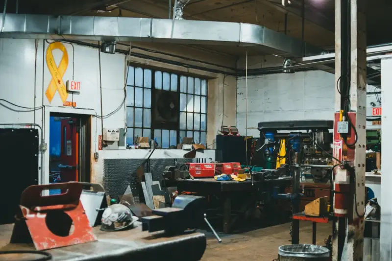Machine shop with drill presses, workbenches and tool boards under tall windows