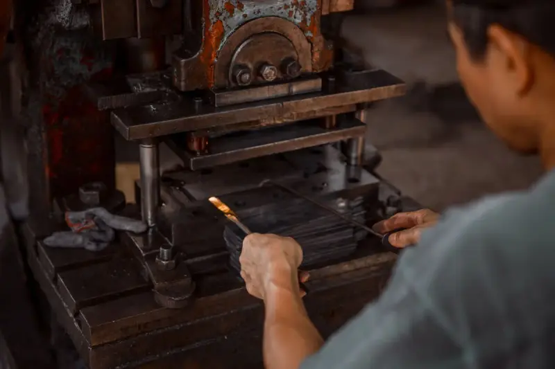 Operator feeding a steel strip into the die of a heavy punch press