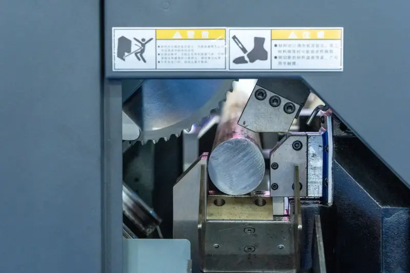 Circular saw blade clamped against a round steel bar inside a cutting machine