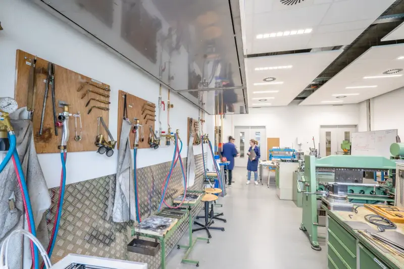 Bright metalworking training shop with tool boards, workbenches and green machines