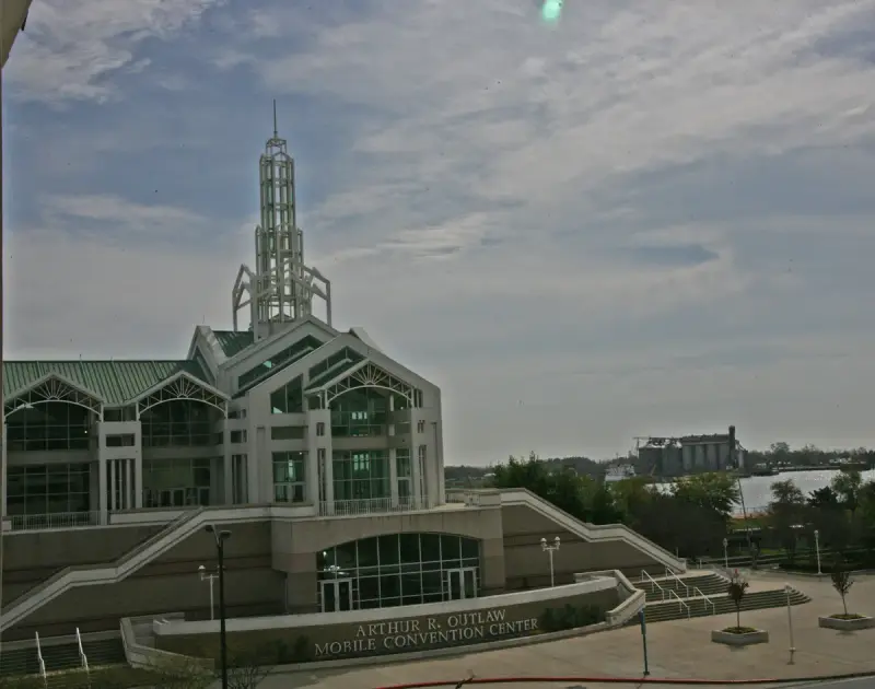 The Arthur R. Outlaw Mobile Convention Center with its white spire and green roofs beside the Mobile River