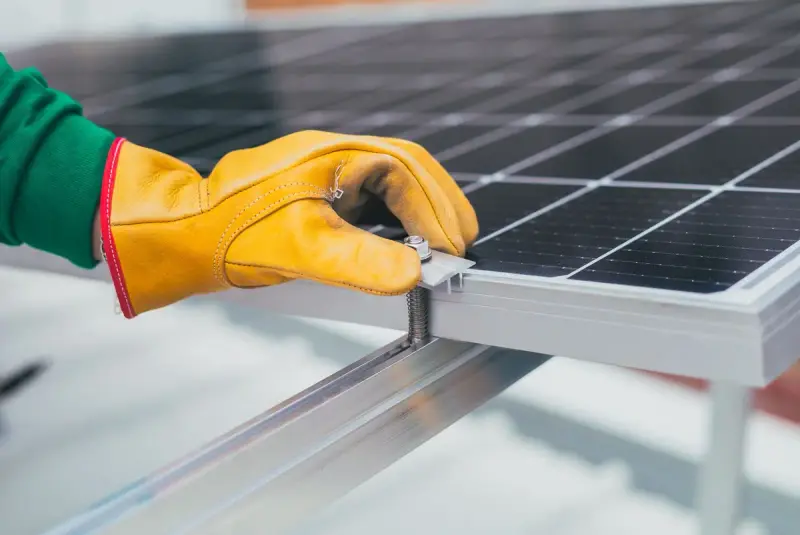 Gloved hand tightening a bolt on a solar panel mounting rail