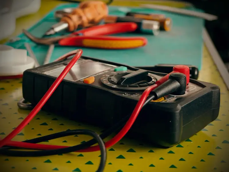 Multimeter and hand tools on a workbench ready for testing