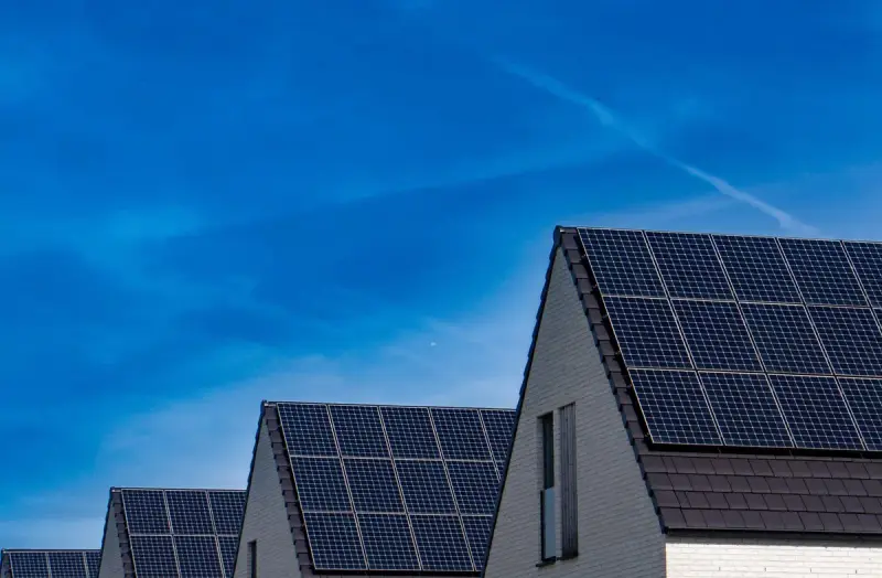 Row of modern homes with rooftop solar panels under a bright blue sky
