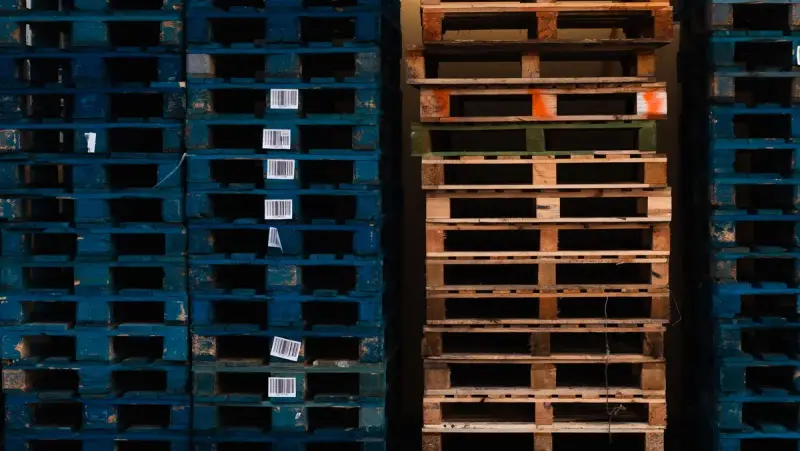 Stacked wooden pallets with barcode tags in a warehouse