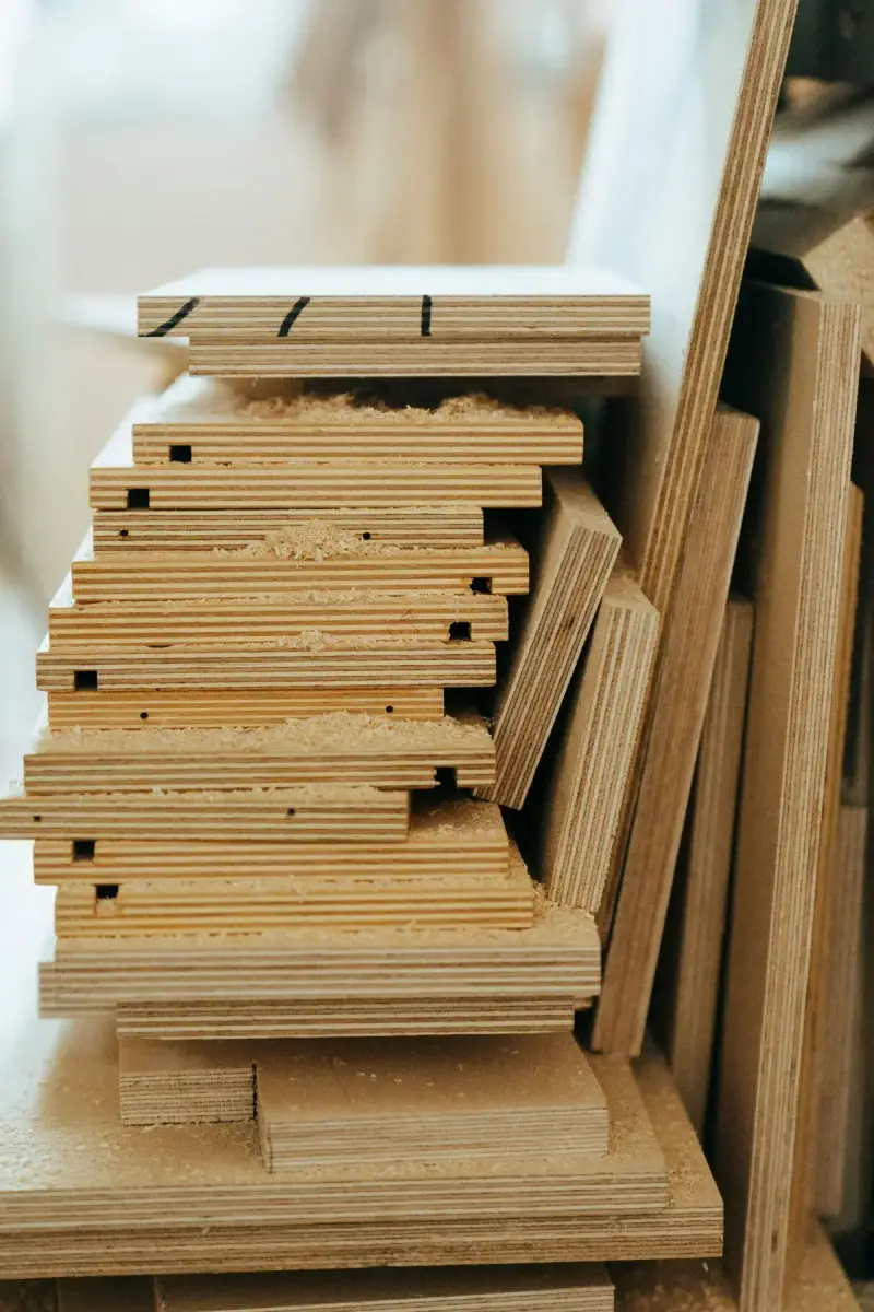 Stacked plywood sheets in a workshop showing their edges